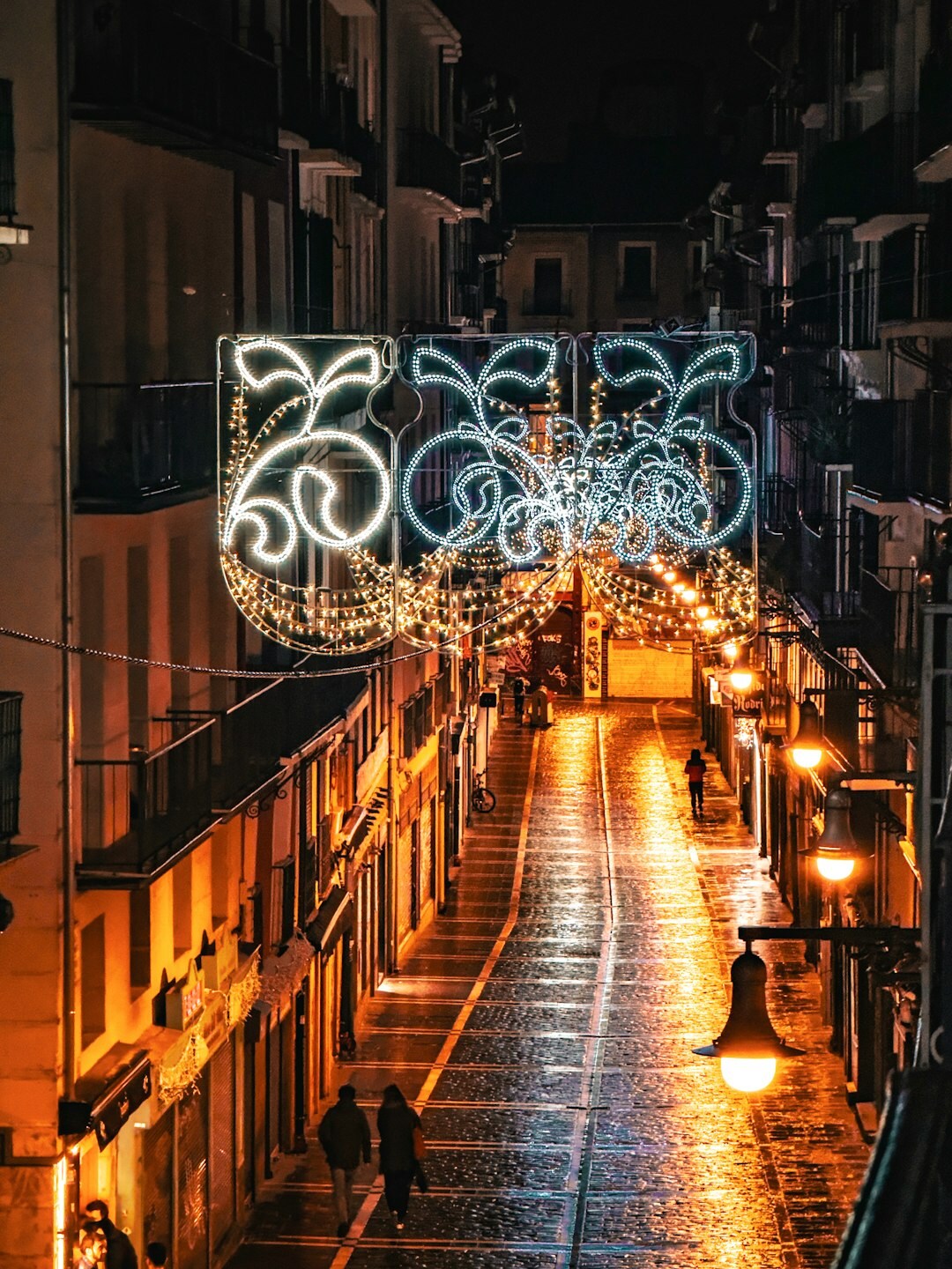 Calle urbana bajo la lluvia por la noche con reflejos de luces